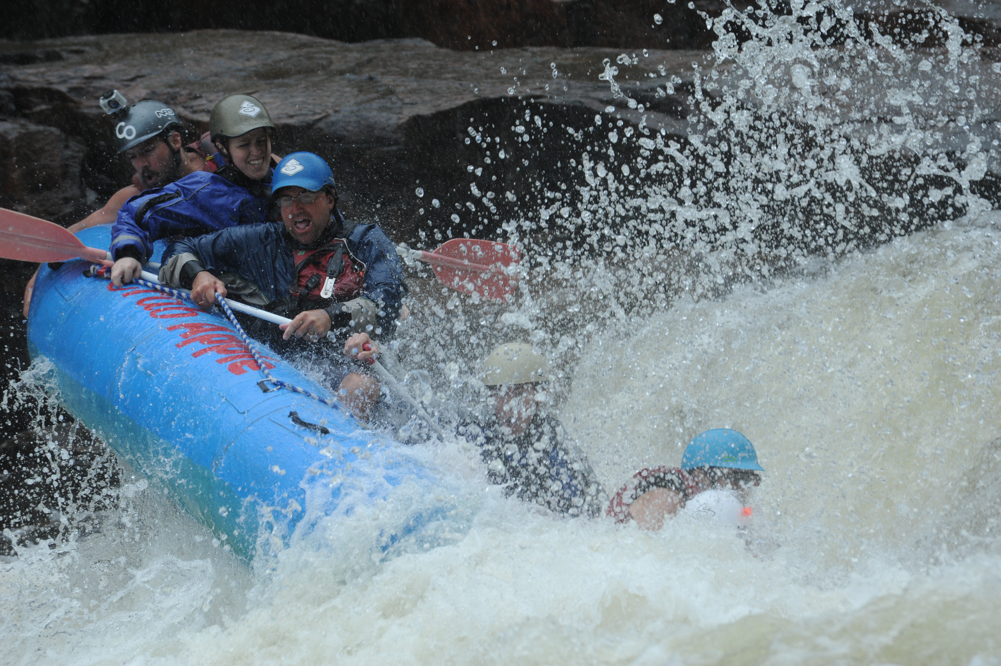 rafters holding onto the raft rope as they fall sideways down the river