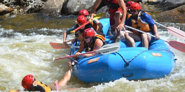 Rafter reaching out to a friend who has fallen in the river.