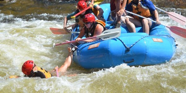 Rafter reaching out to a friend who has fallen in the river.