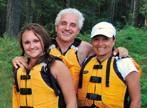 Family of three getting ready to raft down a river.