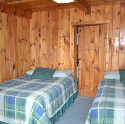 wooden interior bedroom including two beds with plaid sheets