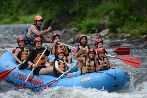 Summer campers rafting down a river.