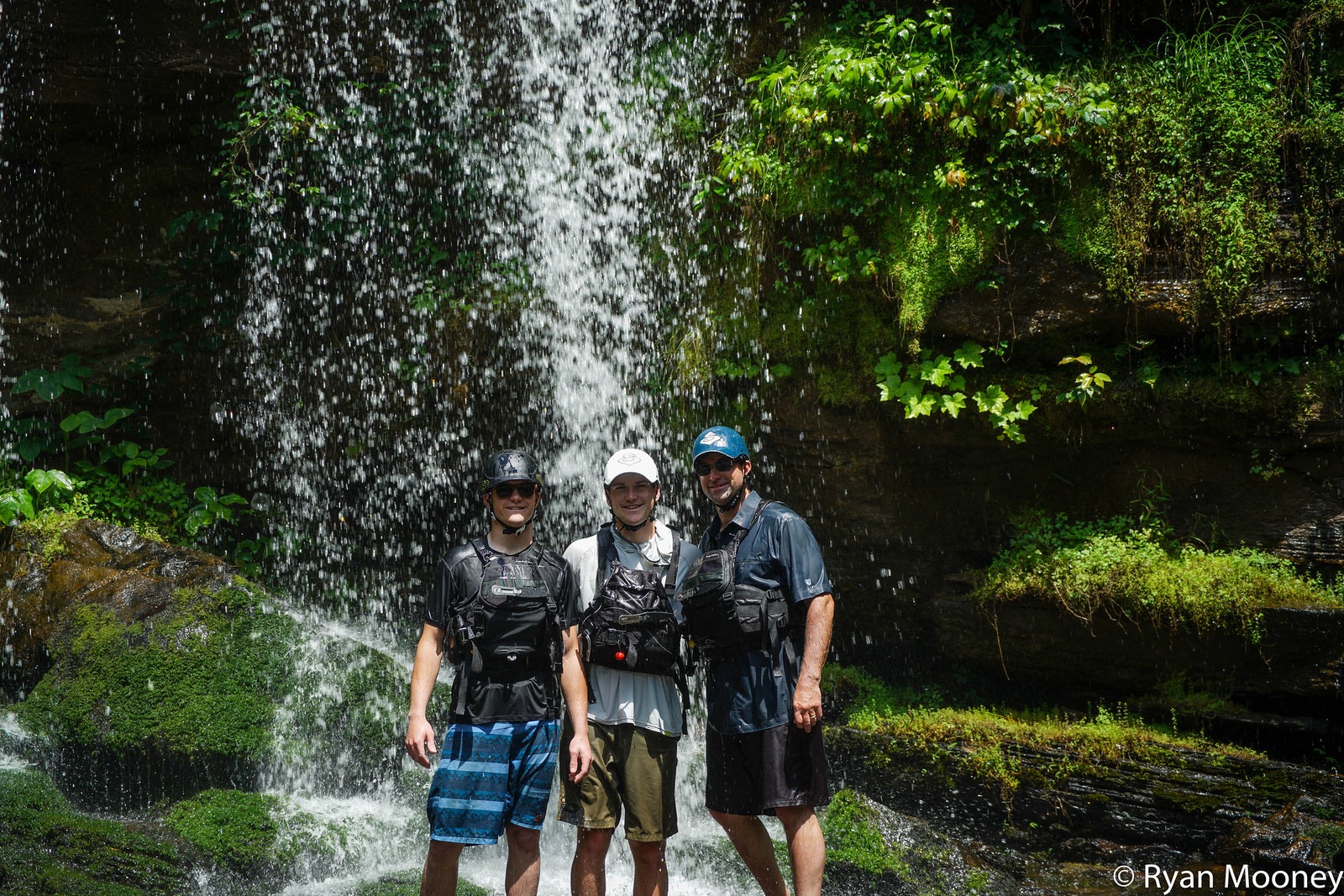 Three members of the Crap Apple team under a waterfall.