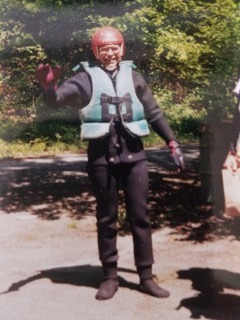 man in life vest and red helmet waiving to the camera