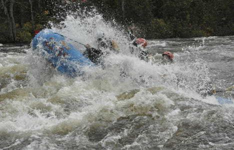 group of rafters getting flipped over by a large wave