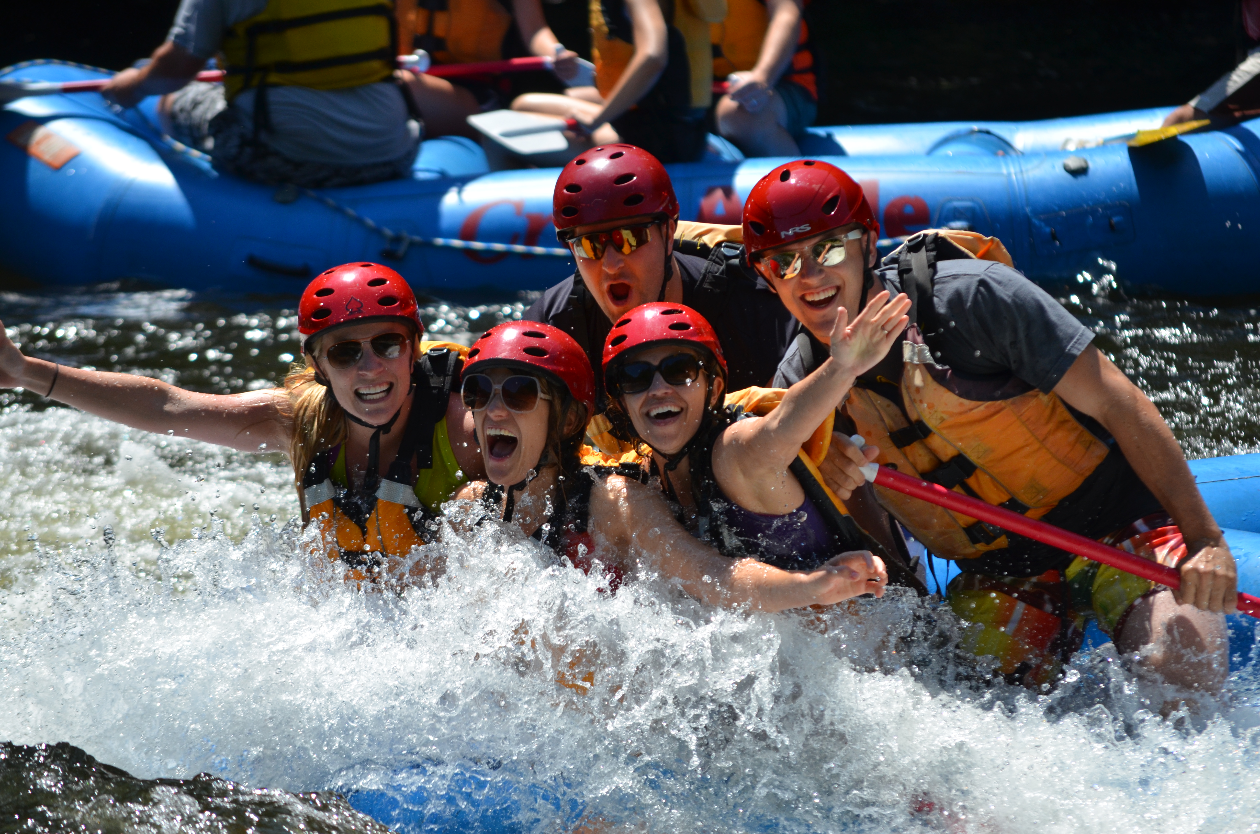 three women smiling in front of two men as they all pose for a picture in the water