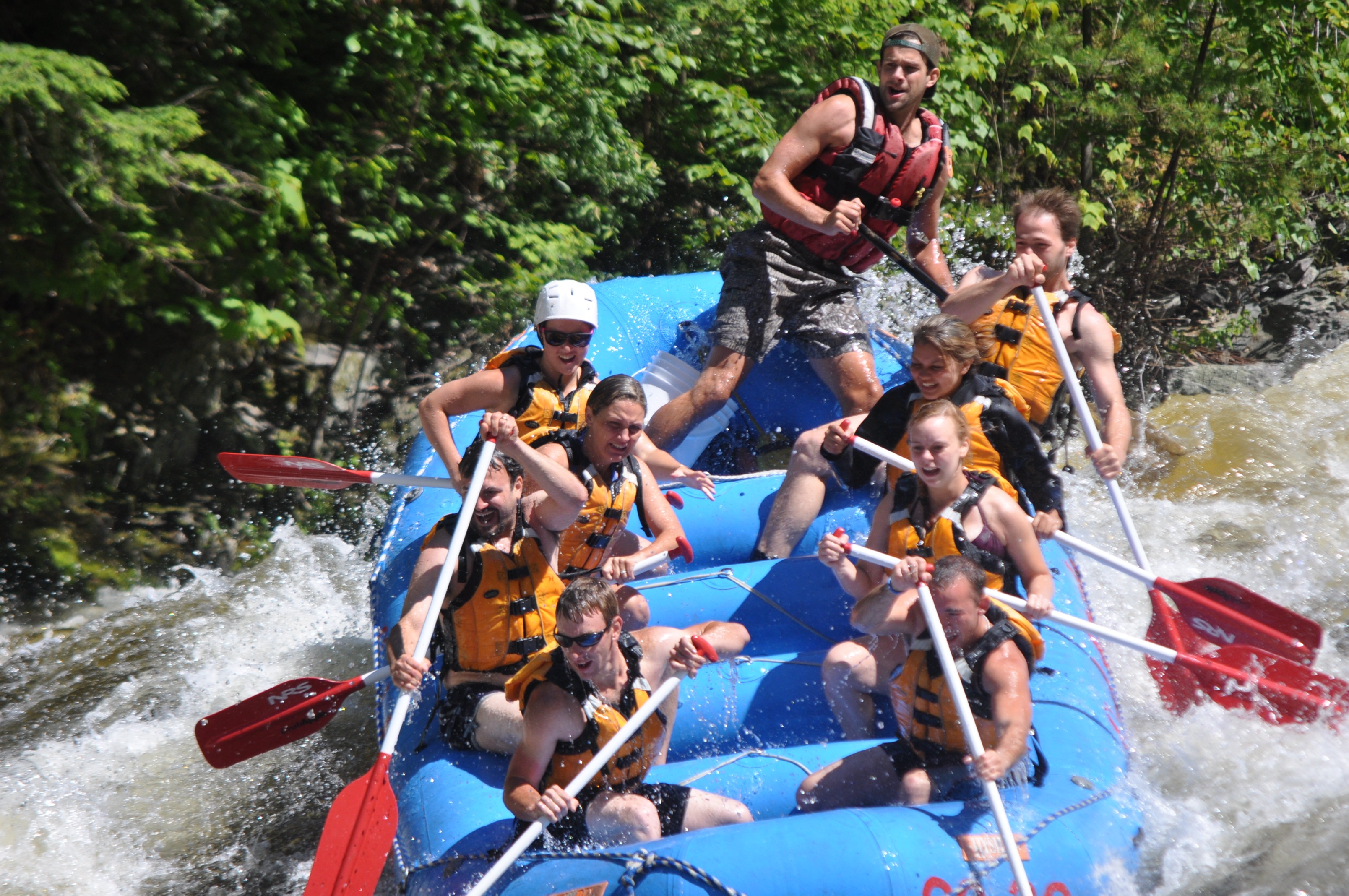 group of rafters going downhill as the back of the raft lifts in the air