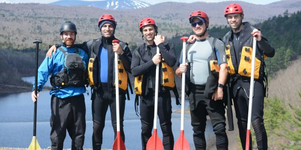 five men posing with their paddles onshore