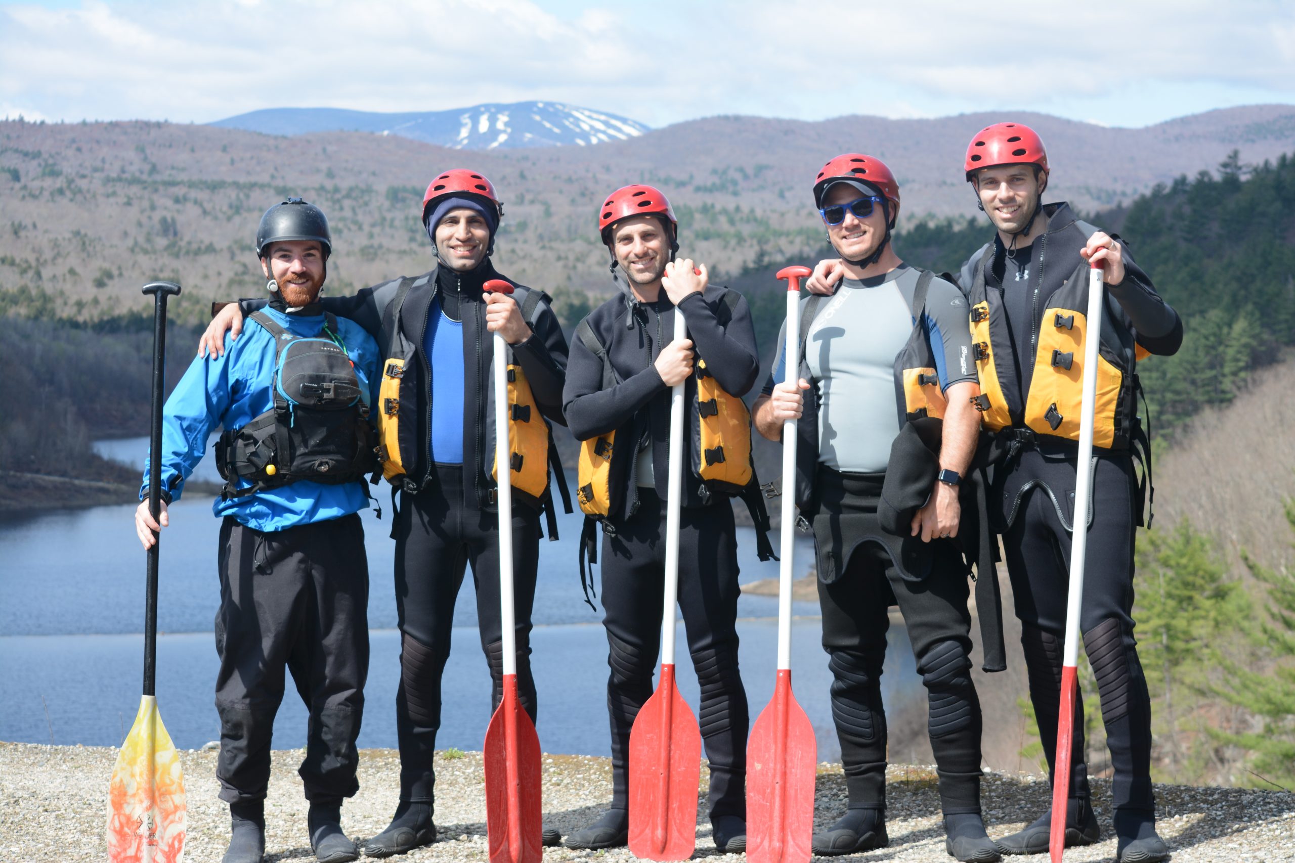 five men posing with their paddles onshore